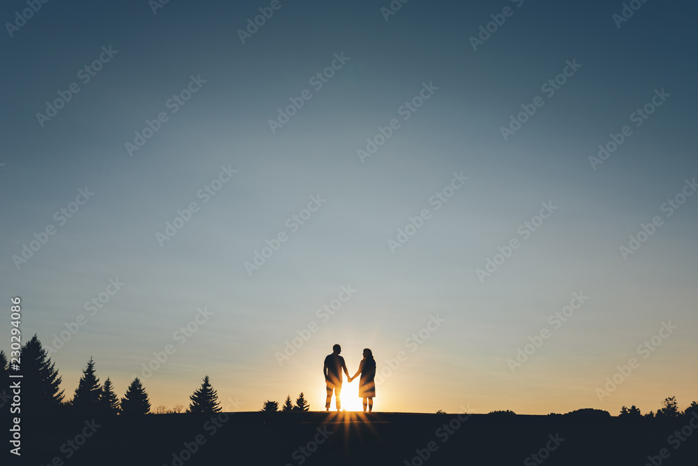 Silhouette of couples who holding hands climbs the hill