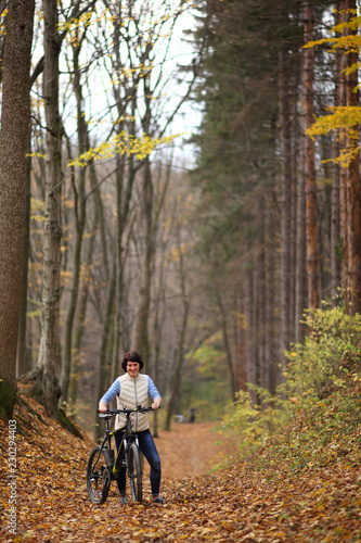 The girl on a bike in the forest. Beautiful young woman posing for the camera in the autumn forest.