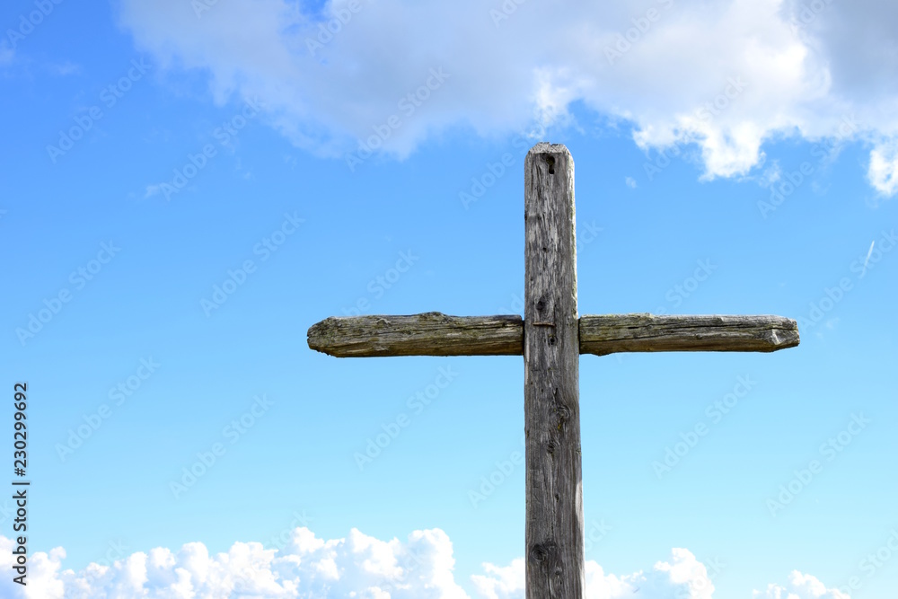 Wetterkreuz aus Holz, freigestellt vor blauen Hintergrund