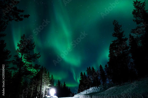 Fotografie, Obraz Large lamp illuminating the countryside for tourists to observe aurora borealis