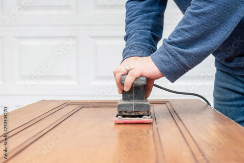 Bild auf Leinwand Closeup of man using power sander to refinish a door