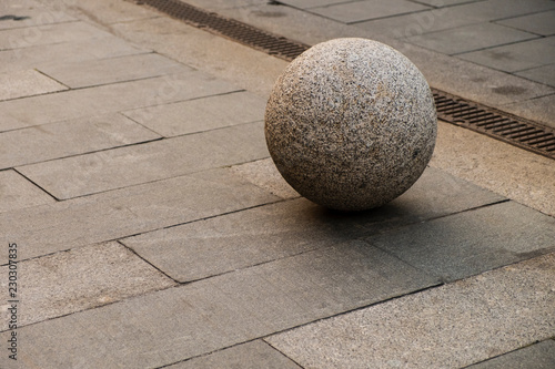 gray pavement, a stone ball lies on the road.