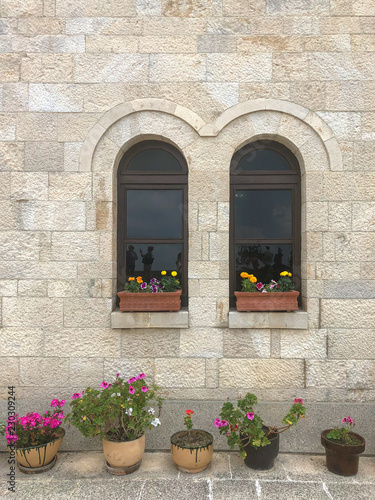 Home exterior with window decorated by flowers and reflections of people at Kruja, Albania