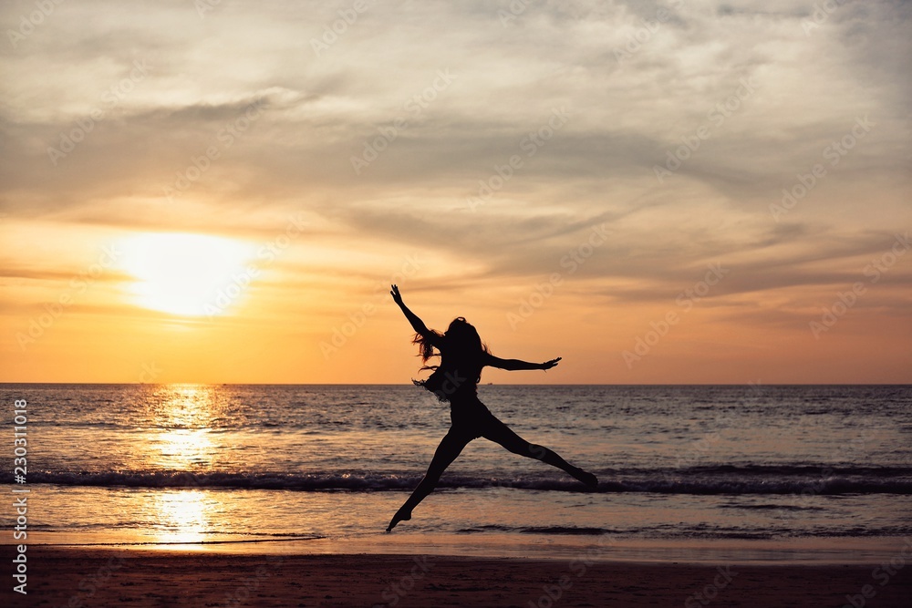 beautiful girl jump on an orange sunset on the background of the sea.