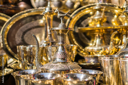 A display of bright golden brass pitchers and trays