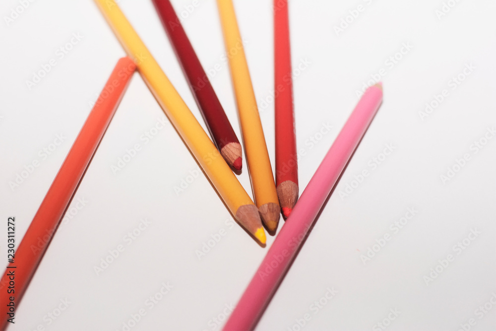 An arrangement of warm colored pencils on a paper white background An arrangement of warm colored pencils on a paper white background