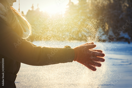 Female hands in red gloves clap their hands with snow. Winter Concept. Sunny day
