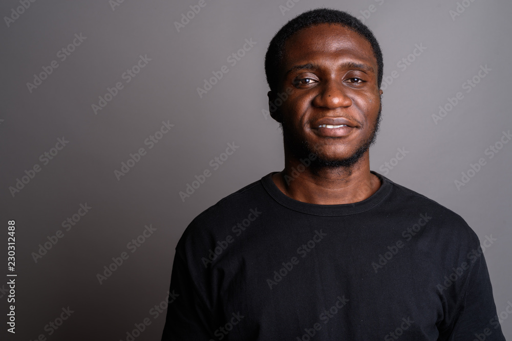 Young African man wearing black shirt against gray background Young African man wearing black shirt against gray background