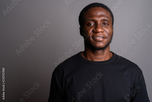 Young African man wearing black shirt against gray background