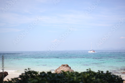 yacht goes by the sea, blue sky, sandy beach.