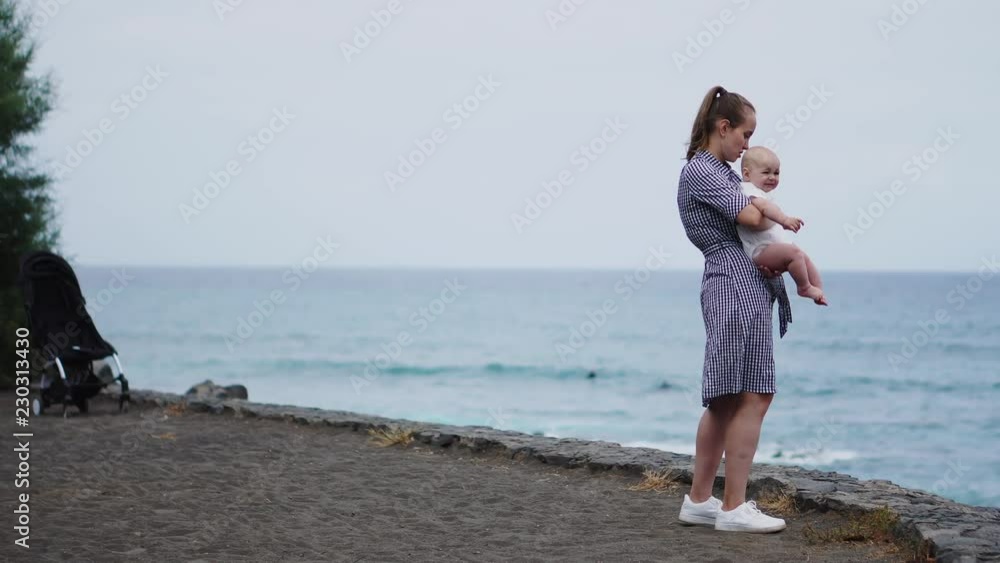 Devoted mother and baby cuddling, spending bonding quality time observing bright blue cloudscape. Attentive parenting and family lifestyle concept. Nature and people background. Devoted mother and baby cuddling, spending bonding quality time observing bright blue cloudscape. Attentive parenting and family lifestyle concept. Nature and people background.