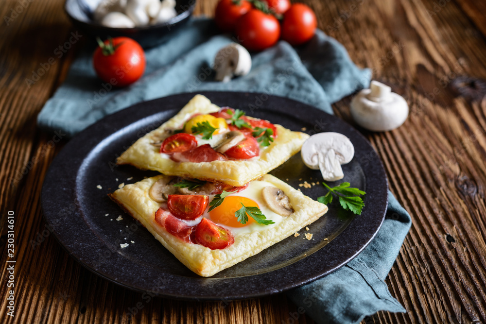 Puff pastry pies with egg, bacon, mushrooms and tomato