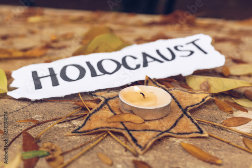 Inscription Holocaust. Star of David and candle on autumn leaves photo