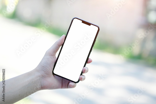 Mock up smartphone of hand holding black mobile phone with blank white screen