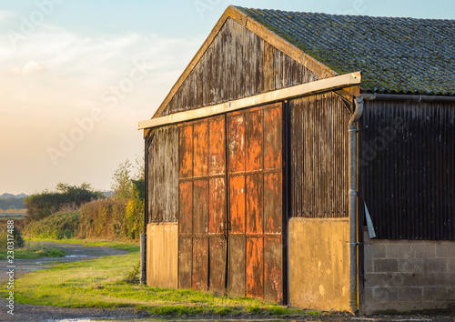 Barn on farmland with metal red and rusty doors. photo