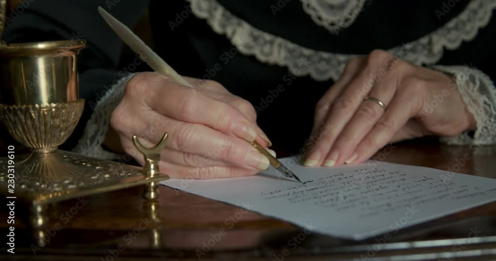 Lit by natural light the aged hands of an old Caucasian woman from the Victorian era using an ornate inkwell and dip pen to write a letter. Lit by natural light the aged hands of an old Caucasian woman from the Victorian era using an ornate inkwell and dip pen to write a letter.