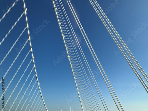 Fototapeta Naklejka Na Ścianę i Meble -  detail close up o fwhite steel bridge suspension wires against blue sky