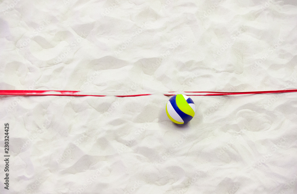 Colorful volleyball ball and red line on top of the sand.