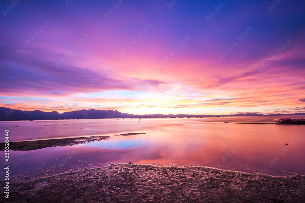 Beautiful sunset on Lake Tahoe with bright purple, pinks and oranges in the sky. Long exposure, calm water