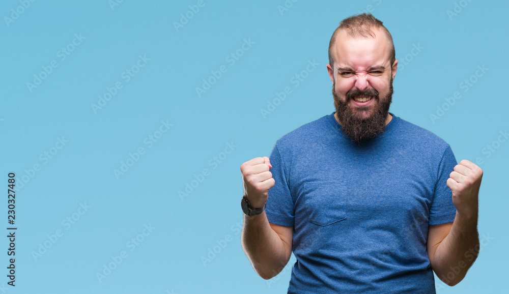 Young caucasian hipster man over isolated background celebrating surprised and amazed for success with arms raised and open eyes. Winner concept. Young caucasian hipster man over isolated background celebrating surprised and amazed for success with arms raised and open eyes. Winner concept.