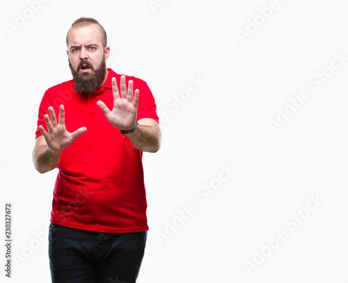 Young caucasian hipster man wearing red shirt over isolated background afraid and terrified with fear expression stop gesture with hands, shouting in shock. Panic concept. © Krakenimages.com