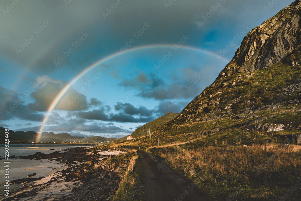 Double Rainbow over the small fishing village with blue sky and cloouds and mountains in the Lofoten Islands, Norway.
