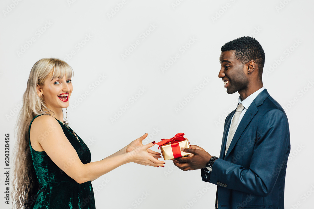 Young woman receiving a beautiful gift from young man in suit Young woman receiving a beautiful gift from young man in suit