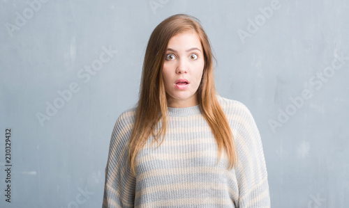 Young adult woman over grey grunge wall scared in shock with a surprise face, afraid and excited with fear expression © Krakenimages.com