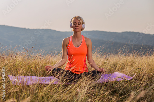 Beautiful woman sittting in lotus position with headphones and meditating in the nature,Padmasana/Lotus position.