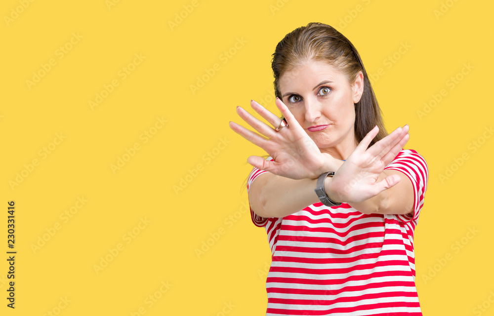 Middle age mature woman wearing casual t-shirt over isolated background Rejection expression crossing arms and palms doing negative sign, angry face Middle age mature woman wearing casual t-shirt over isolated background Rejection expression crossing arms and palms doing negative sign, angry face