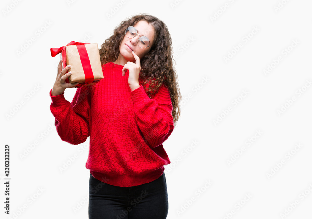 Young brunette girl holding a gift over isolated background serious face thinking about question, very confused idea Young brunette girl holding a gift over isolated background serious face thinking about question, very confused idea