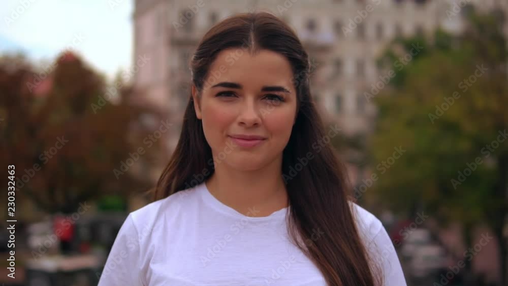 young l woman with beautiful long hair posing outdoors showing thumb up. happy girl smiling looking at the camera young l woman with beautiful long hair posing outdoors showing thumb up. happy girl smiling looking at the camera