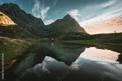 Fototapeta Naklejka Na Ścianę i Meble -  Sunset mountains in the background near Tangstad in lofoten Islands, Norway. Beautiful reflection with pink and red sky.