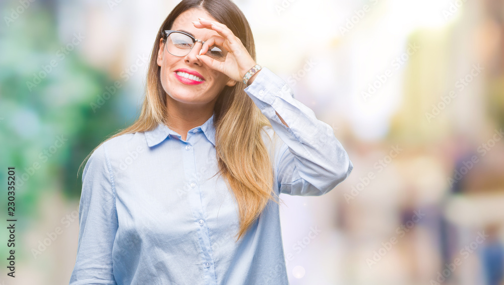 Young beautiful business woman wearing glasses over isolated background doing ok gesture with hand smiling, eye looking through fingers with happy face.