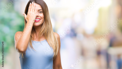 Young beautiful elegant business woman over isolated background covering one eye with hand with confident smile on face and surprise emotion.