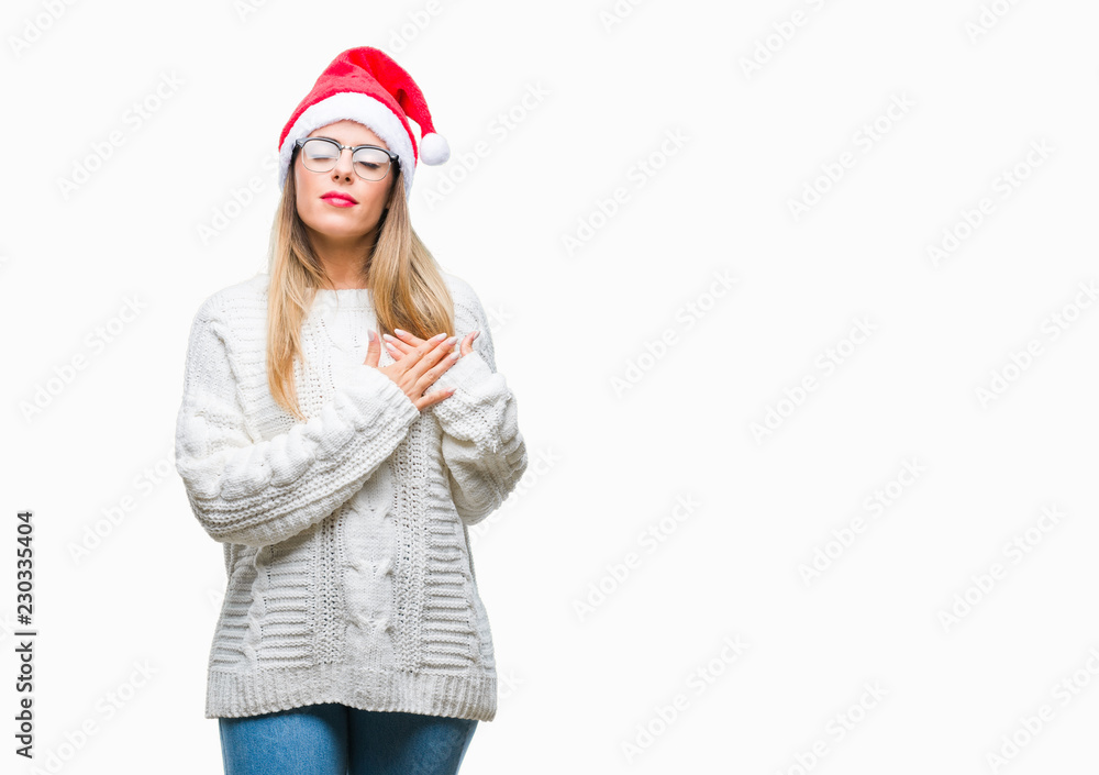 Young beautiful woman wearing christmas hat over isolated background smiling with hands on chest with closed eyes and grateful gesture on face. Health concept. Young beautiful woman wearing christmas hat over isolated background smiling with hands on chest with closed eyes and grateful gesture on face. Health concept.