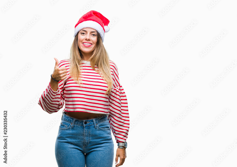 Young beautiful woman wearing christmas hat over isolated background doing happy thumbs up gesture with hand. Approving expression looking at the camera with showing success.