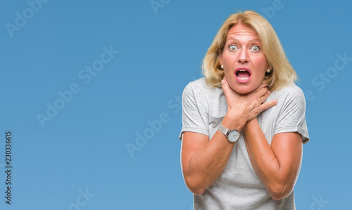 Middle age blonde woman over isolated background shouting and suffocate because painful strangle. Health problem. Asphyxiate and suicide concept.