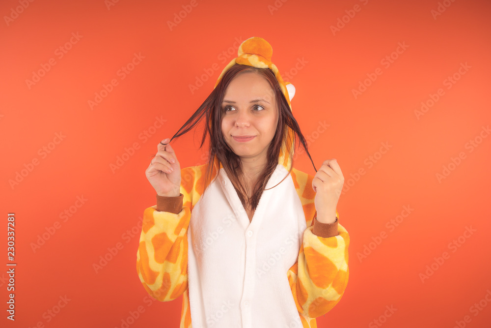 pajamas in the form of a giraffe. emotional portrait of a girl on an orange background. crazy and funny woman in a suit. animator for childrens parties pajamas in the form of a giraffe. emotional portrait of a girl on an orange background. crazy and funny woman in a suit. animator for childrens parties