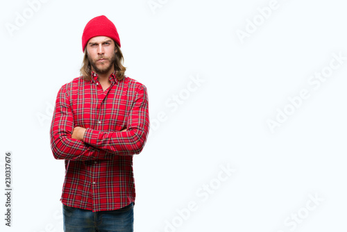 Young handsome man with long hair wearing red cap over isolated background skeptic and nervous, disapproving expression on face with crossed arms. Negative person.