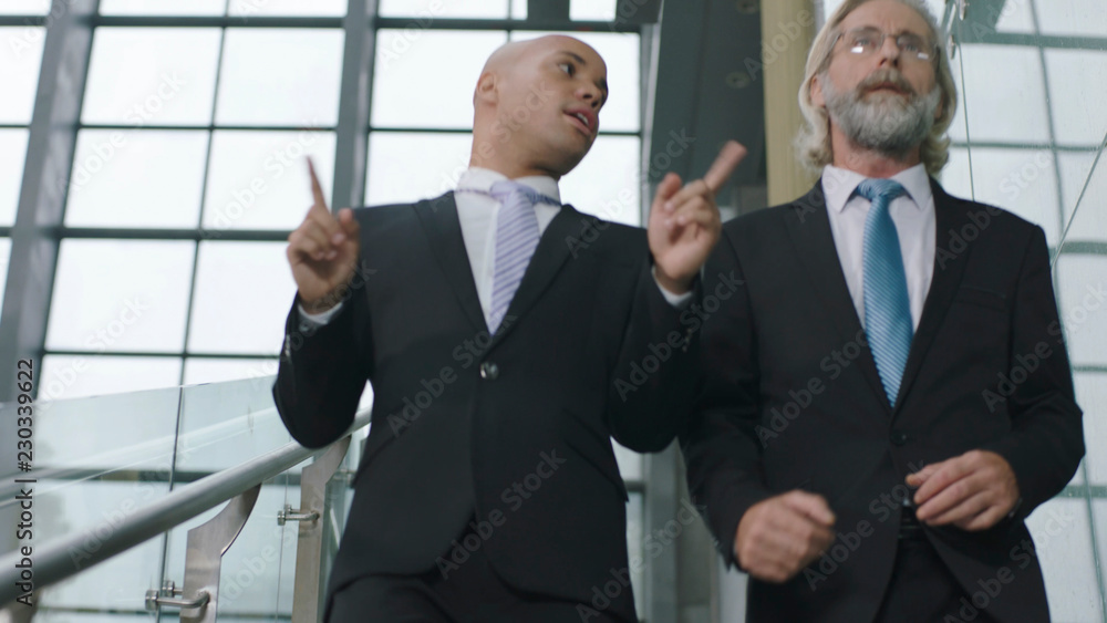 two corporate executives talking while descending stairs