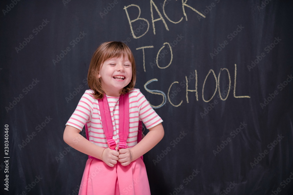 school girl child with backpack writing  chalkboard
