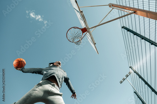 Winning throw. Low angle of a basketball player jumping while doing the winning throw © zinkevych