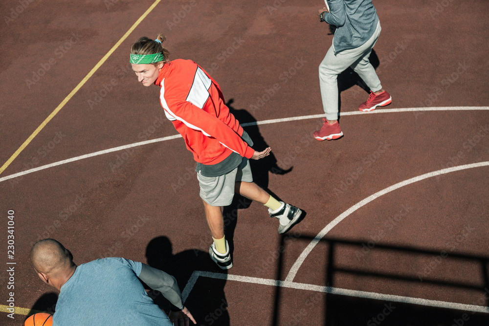 Fototapeta premium My team. Nice young man looking at his team members while standing on the basketball ground