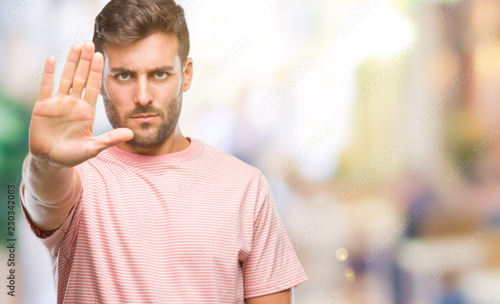 Naklejka premium Young handsome man over isolated background doing stop sing with palm of the hand. Warning expression with negative and serious gesture on the face.