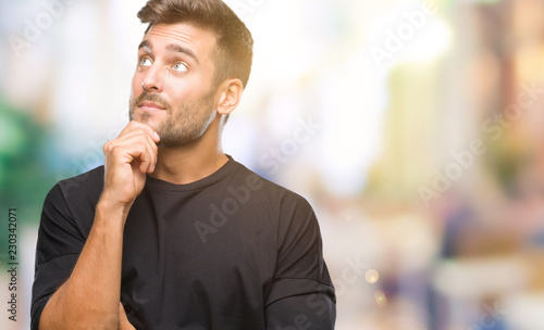 Young handsome man over isolated background with hand on chin thinking about question, pensive expression. Smiling with thoughtful face. Doubt concept. © Krakenimages.com