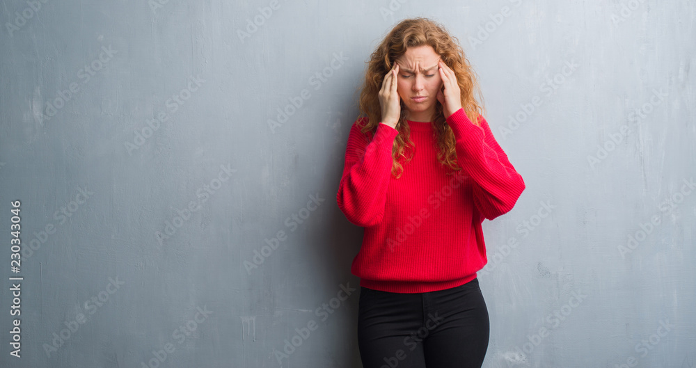 Φωτογραφία Young redhead woman over grey grunge wall wearing red sweater with hand on head for pain in head because stress