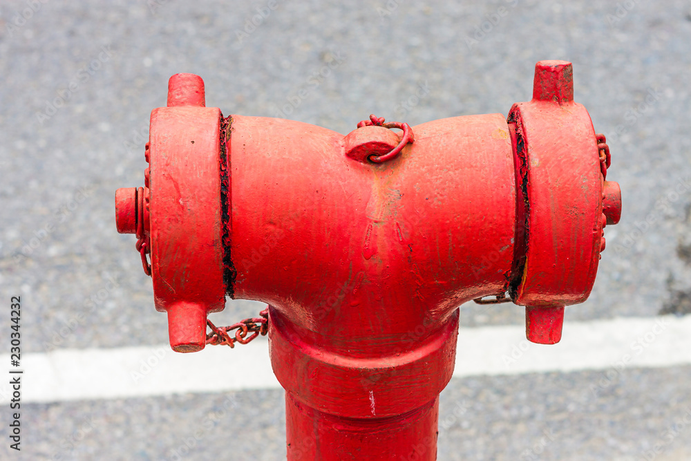 A closeup to a red fire hydrant water pipe near the road. A closeup to a red fire hydrant water pipe near the road.