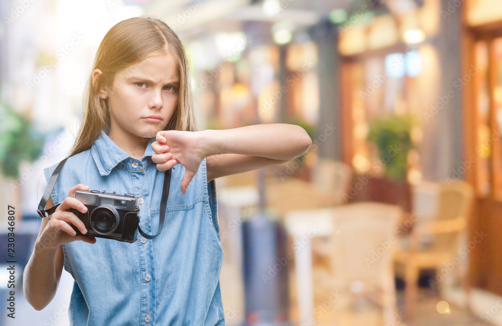 Young beautiful girl taking photos using vintage camera over isolated background with angry face, negative sign showing dislike with thumbs down, rejection concept