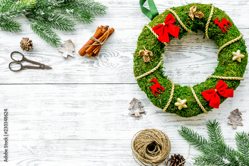 Process of making christmas wreath concept. Green christmas wreath near matherials and instruments, sciccors on white wooden background top view copy space photo